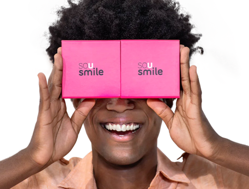 Mulher negra com um reluzente e alegre sorriso branco segurando a caixa do aparelho em frente aos seus olhos.
