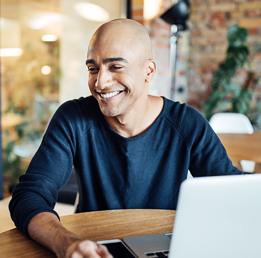 Homem sorrindo enquanto usa um notebook